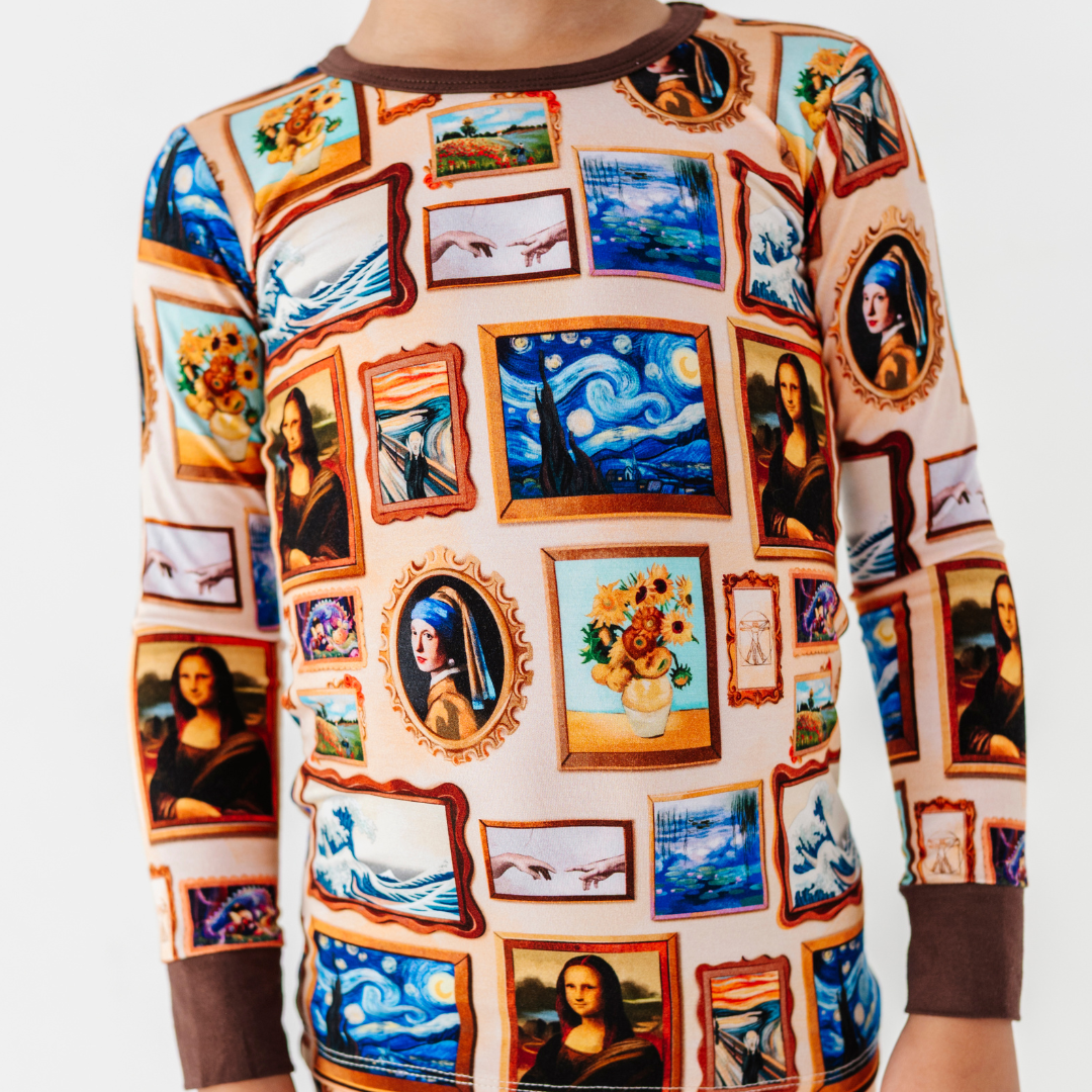 Close-up of a pajama top with a framed classic paintings print and brown collar and cuffs.